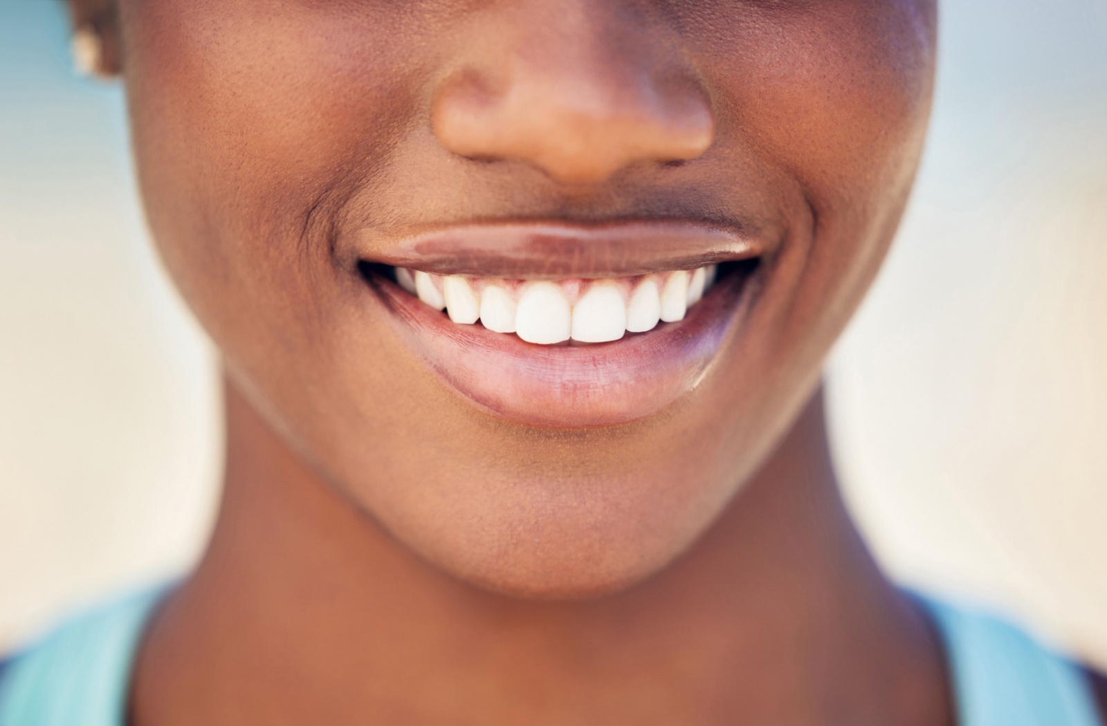 Person smiling with white teeth in natural light with the focus is on their mouth and healthy smile