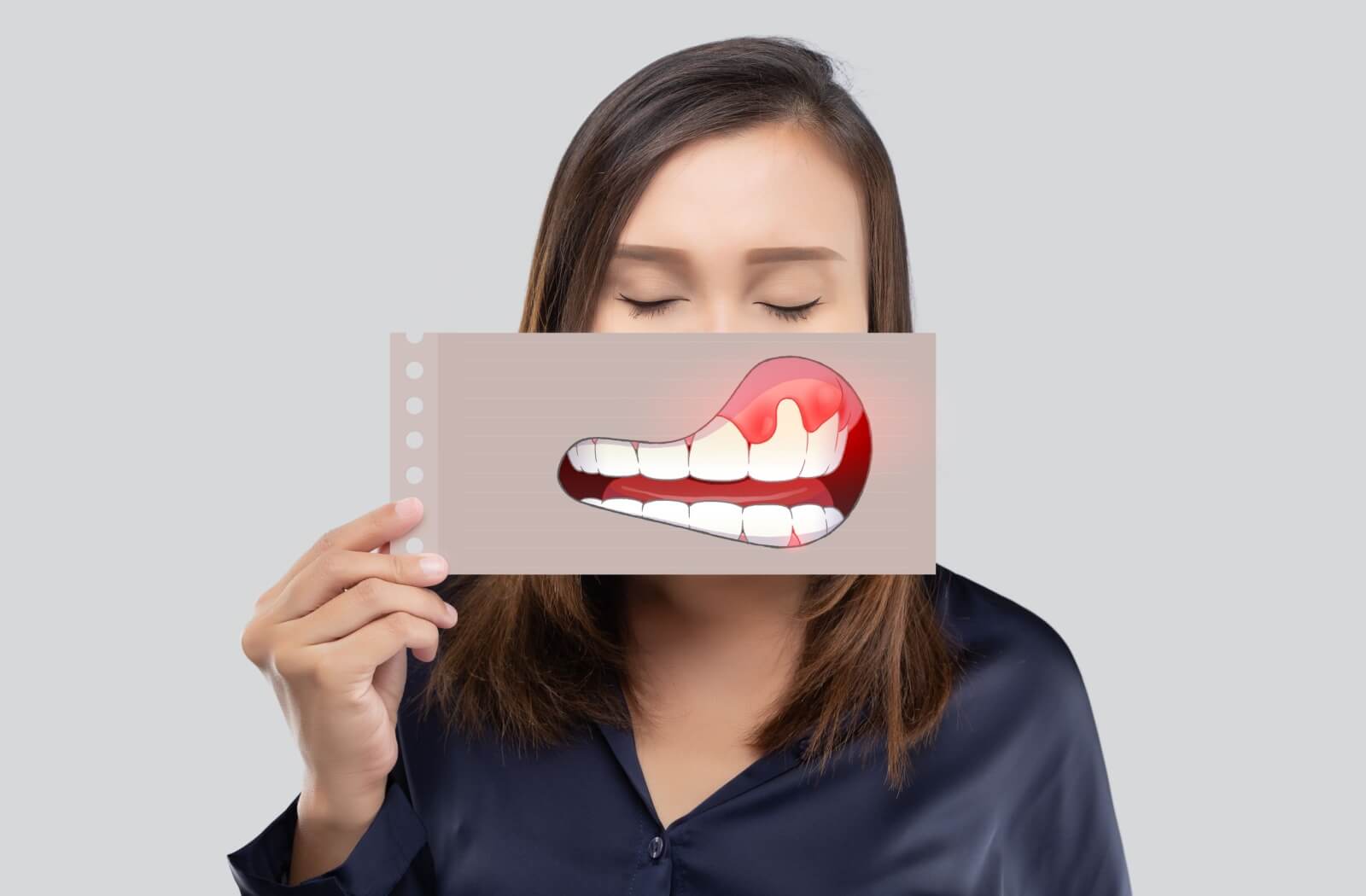 A person holds up an illustration of red, inflamed gums, against their natural smile.